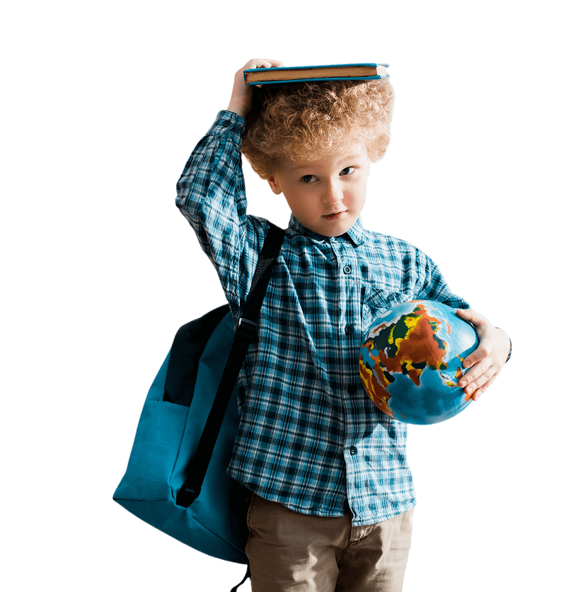 Young boy with a backpack holds a globe in one hand and balances a book on his head, wearing a blue plaid shirt.