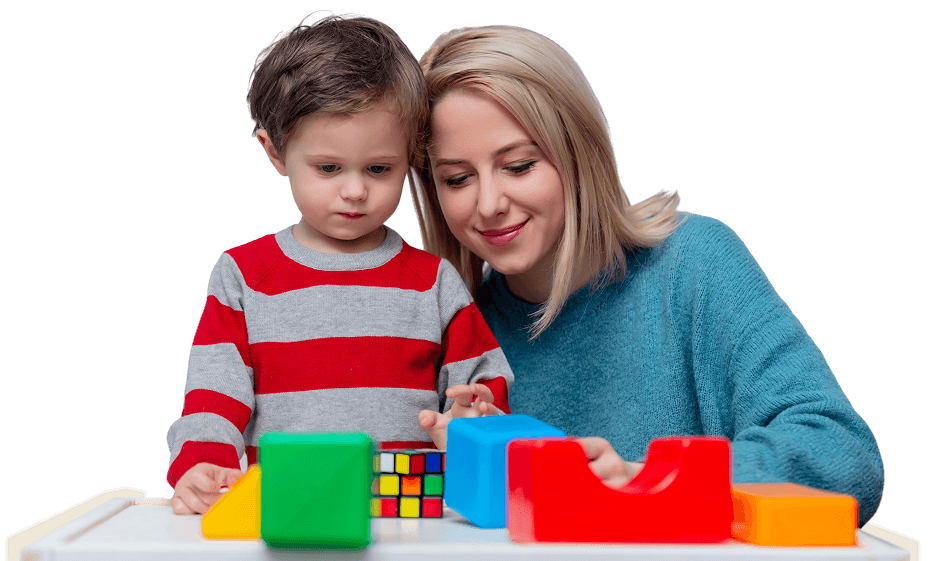 A woman and a young boy sit at a table in a preschool program, playing with colorful geometric blocks and a Rubik’s cube—an engaging scene that highlights the joy of early childhood education.